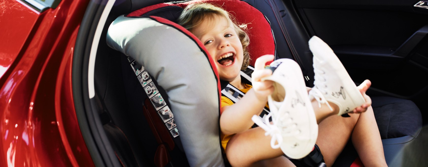 Ett skrattande barn i en bilbarnstol i en säker röd bil från SEAT
