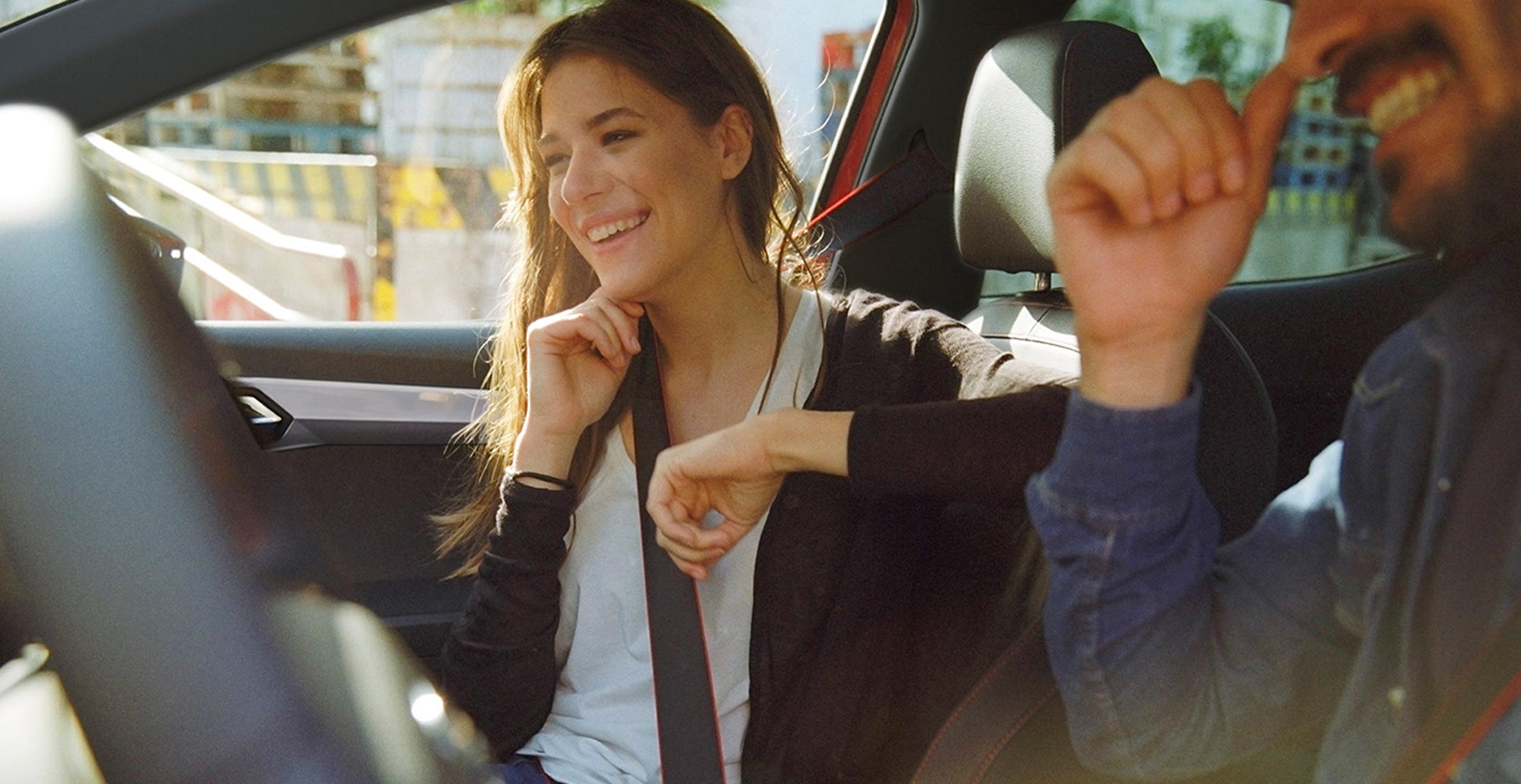 En man som är knappt synlig och en kvinna sitter och skrattar i bil