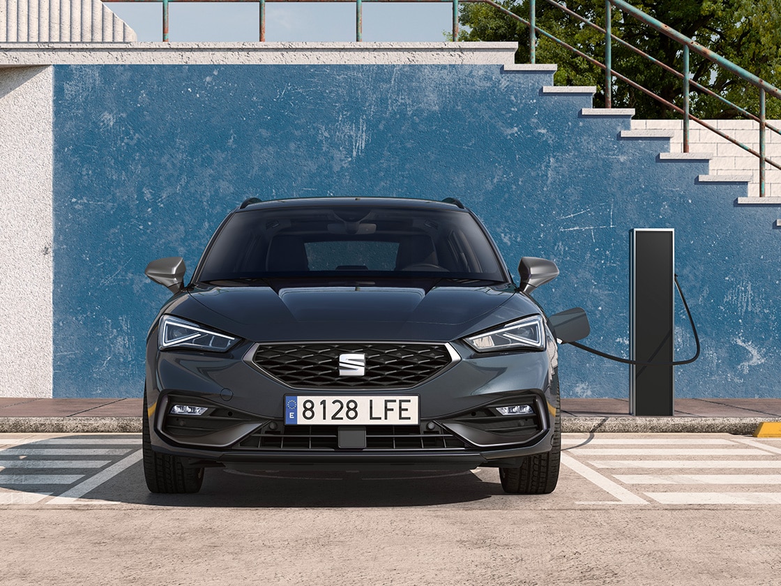 Seat leon  sportstourere hybrid, en hybridelbil, parkerad på en parkeringsplats bredvid en laddstation utomhus och visar upp e manager-funktionen för ett imponerande värde.