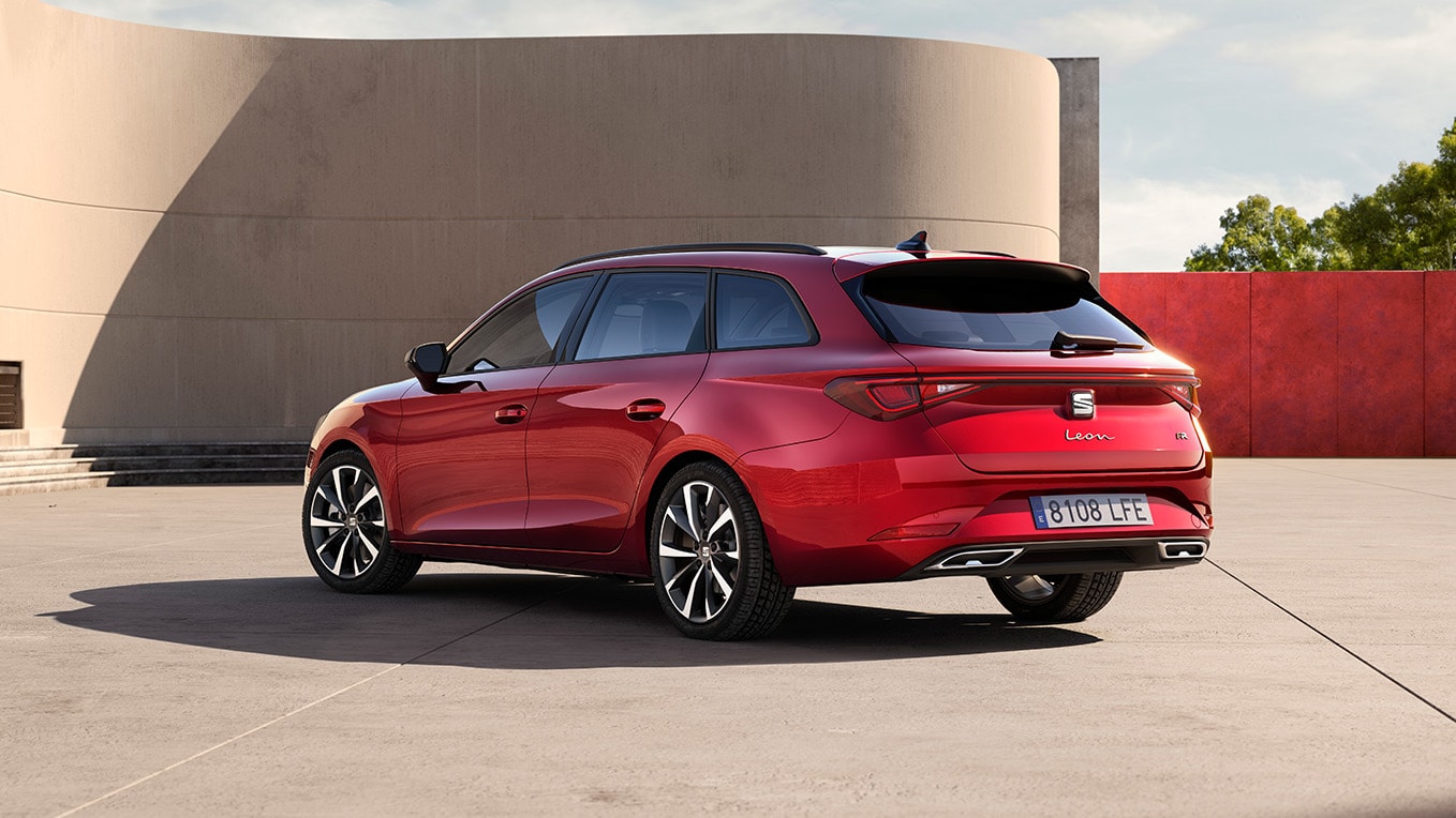 Sidovy bakifrån av kombimodellen med sätet Leon Sporttourer i Desire Red, parkerad mot en byggnadsvägg utomhus. Vyn visar bilens bakpartidesign.