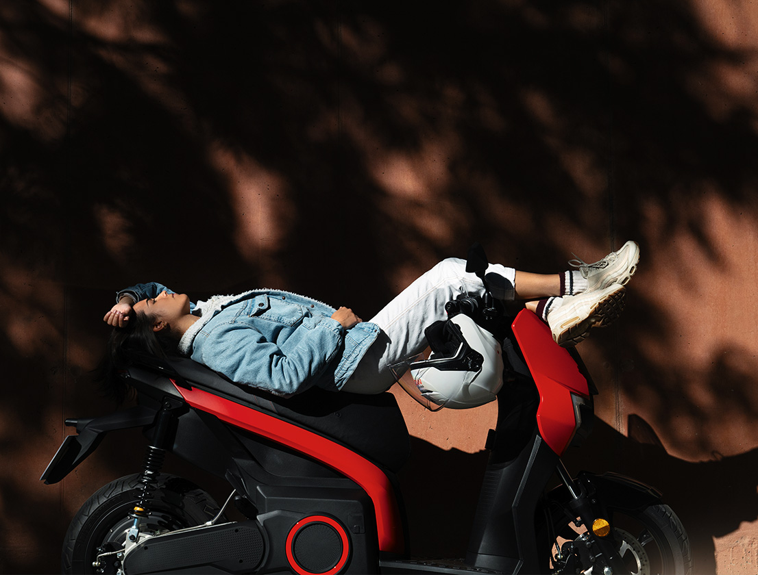 Kvinna som ligger på sin SEAT MÓ 125 elscooter men räckvidd på 137 km