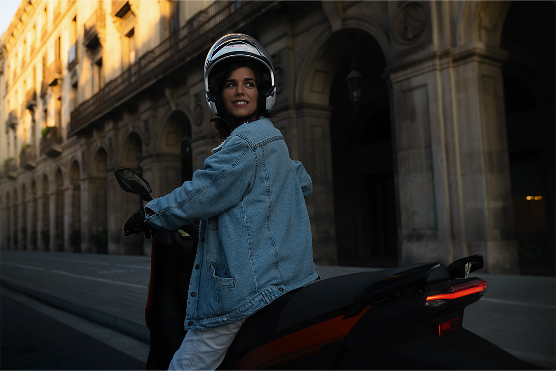 en kvinna som kör sin SEAT MÓ 125 elscooter med en topphastighet på 95 km/h
