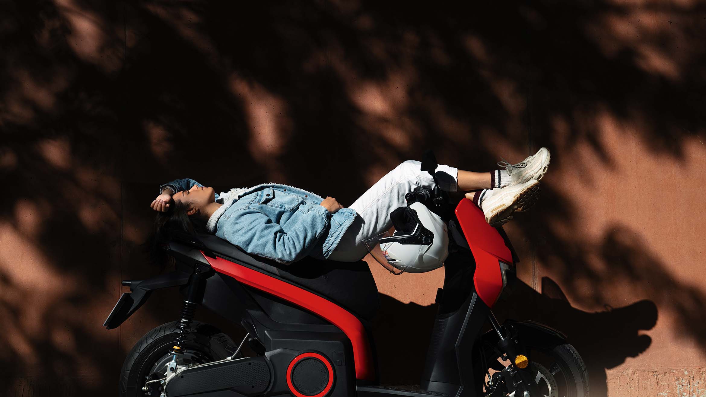 person lying beside their parked SEAT MÓ 65 electric scooter