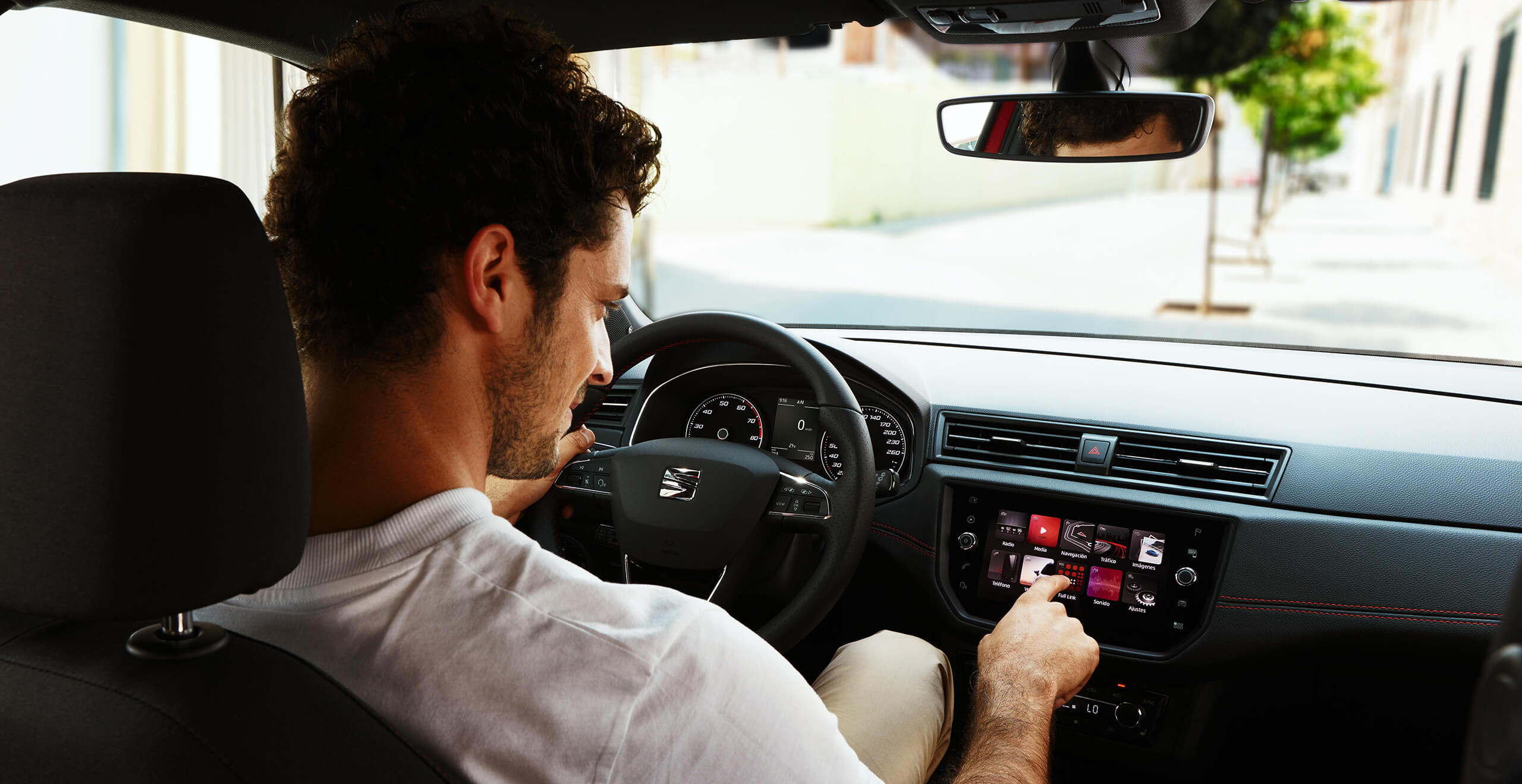 SEAT service och underhåll för nya bilar – interiörvy bakifrån på en manlig förare som trycker på en knapp på instrumentpanelen till en ny SEAT-bil